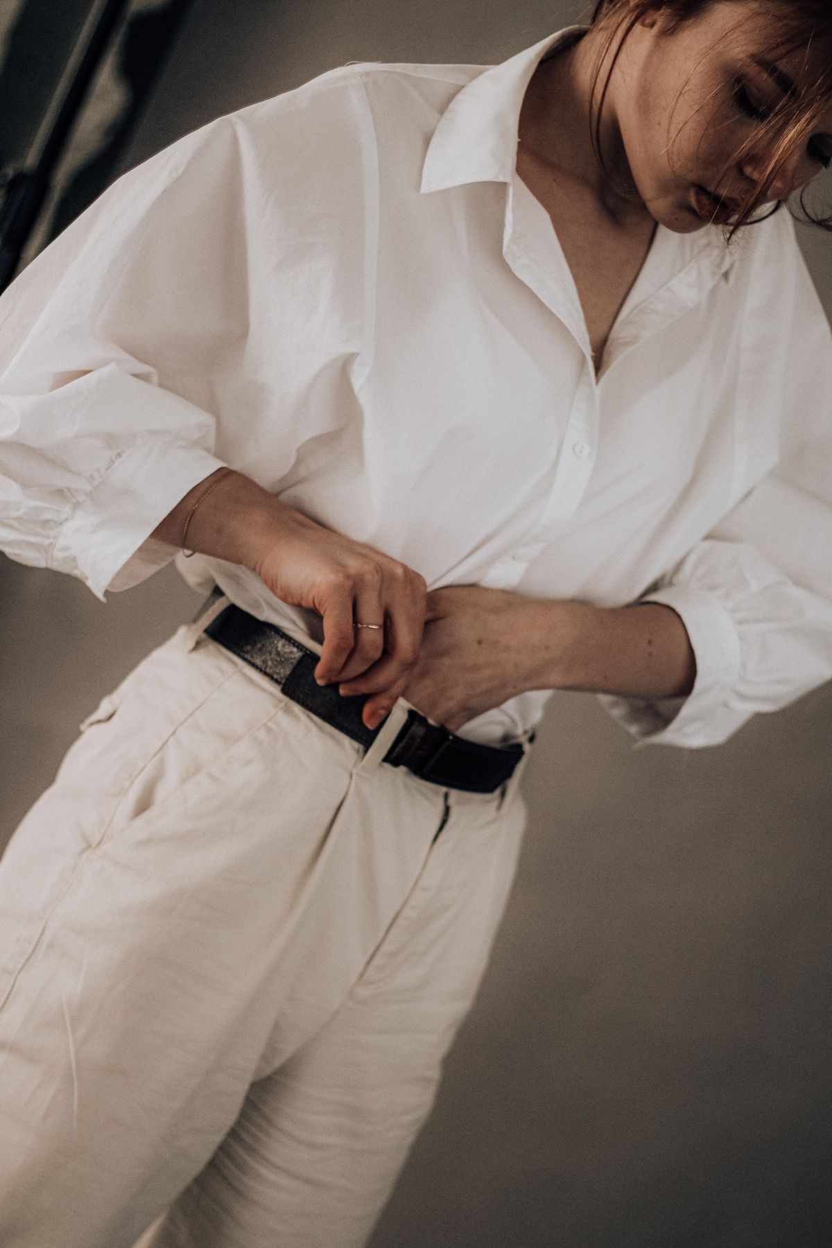 A white shirt being tucked into light trousers
