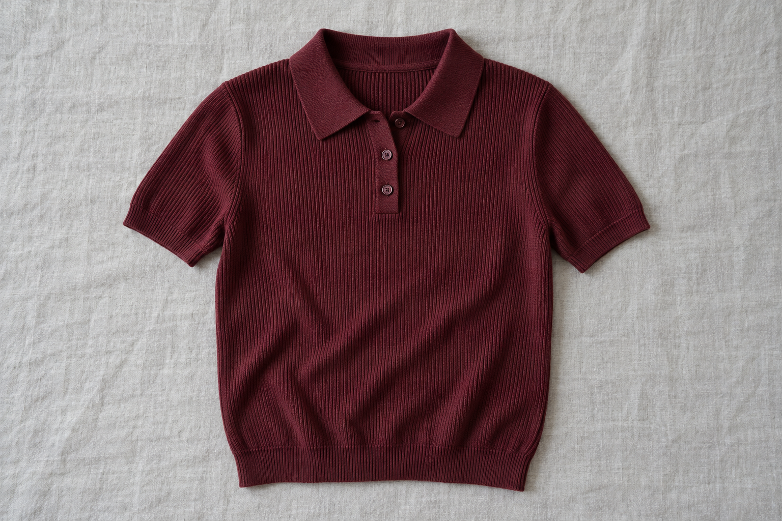 A burgundy knitted polo laid flat on a table