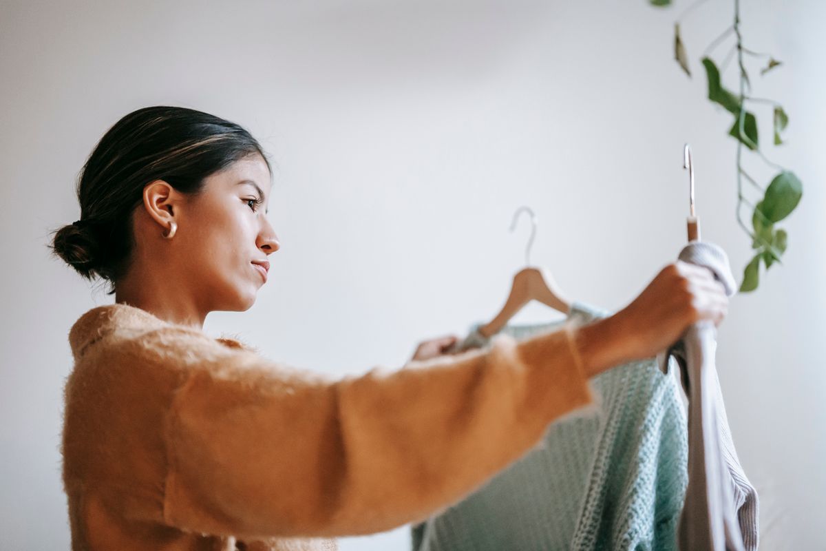 A woman considering a garment from her wardrobe