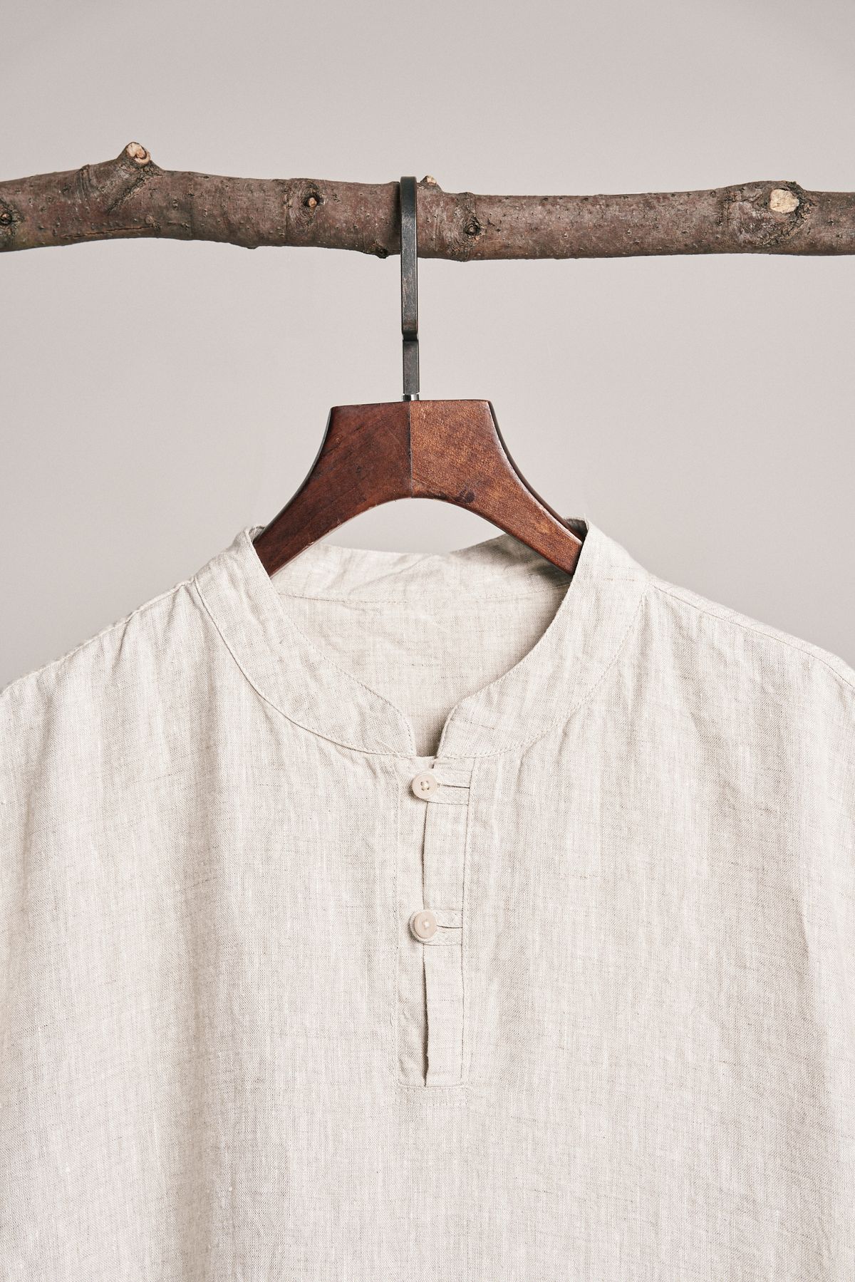 A pale textured shirt hanging from a wooden hanger