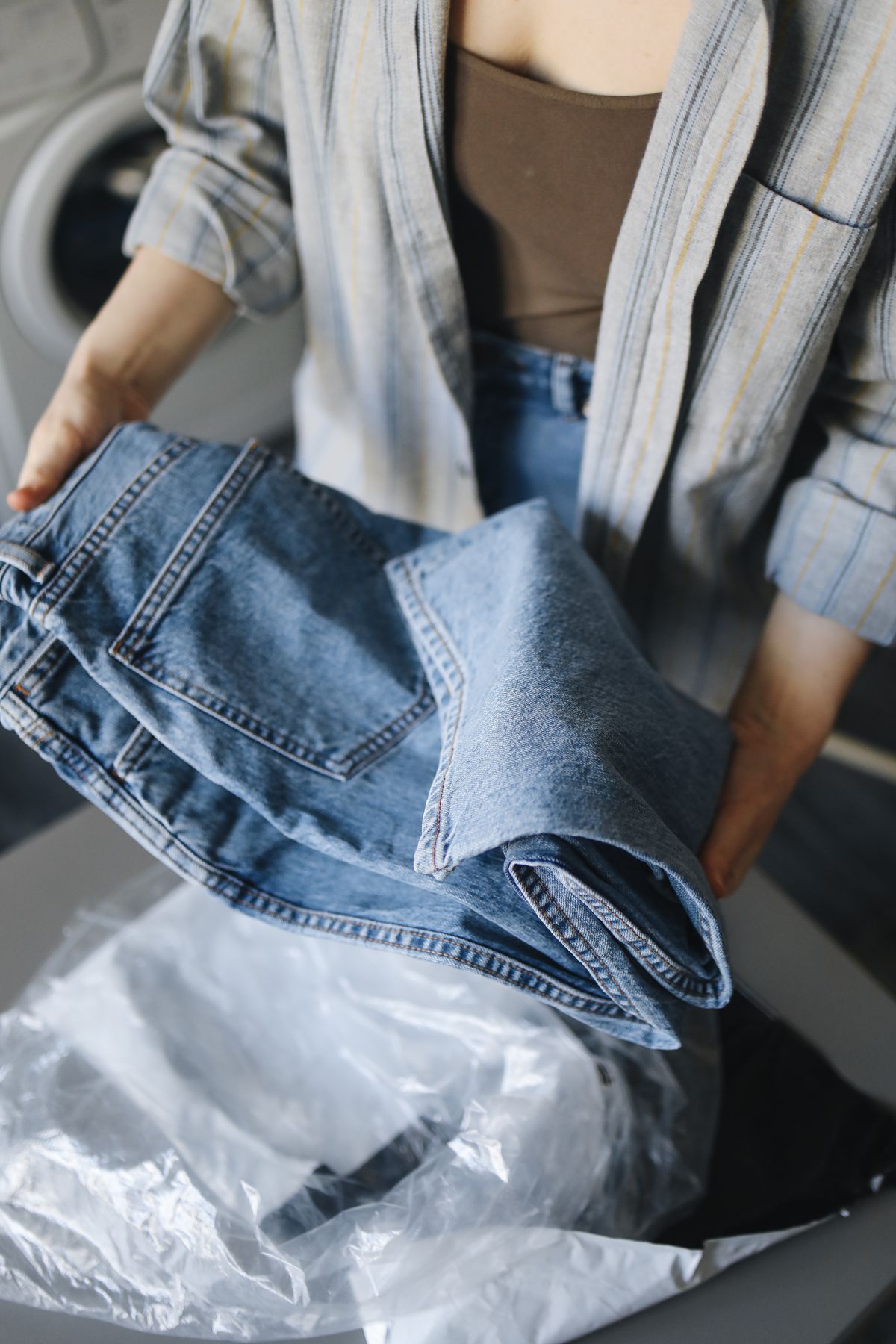 Blue jeans being handled beside other laundry