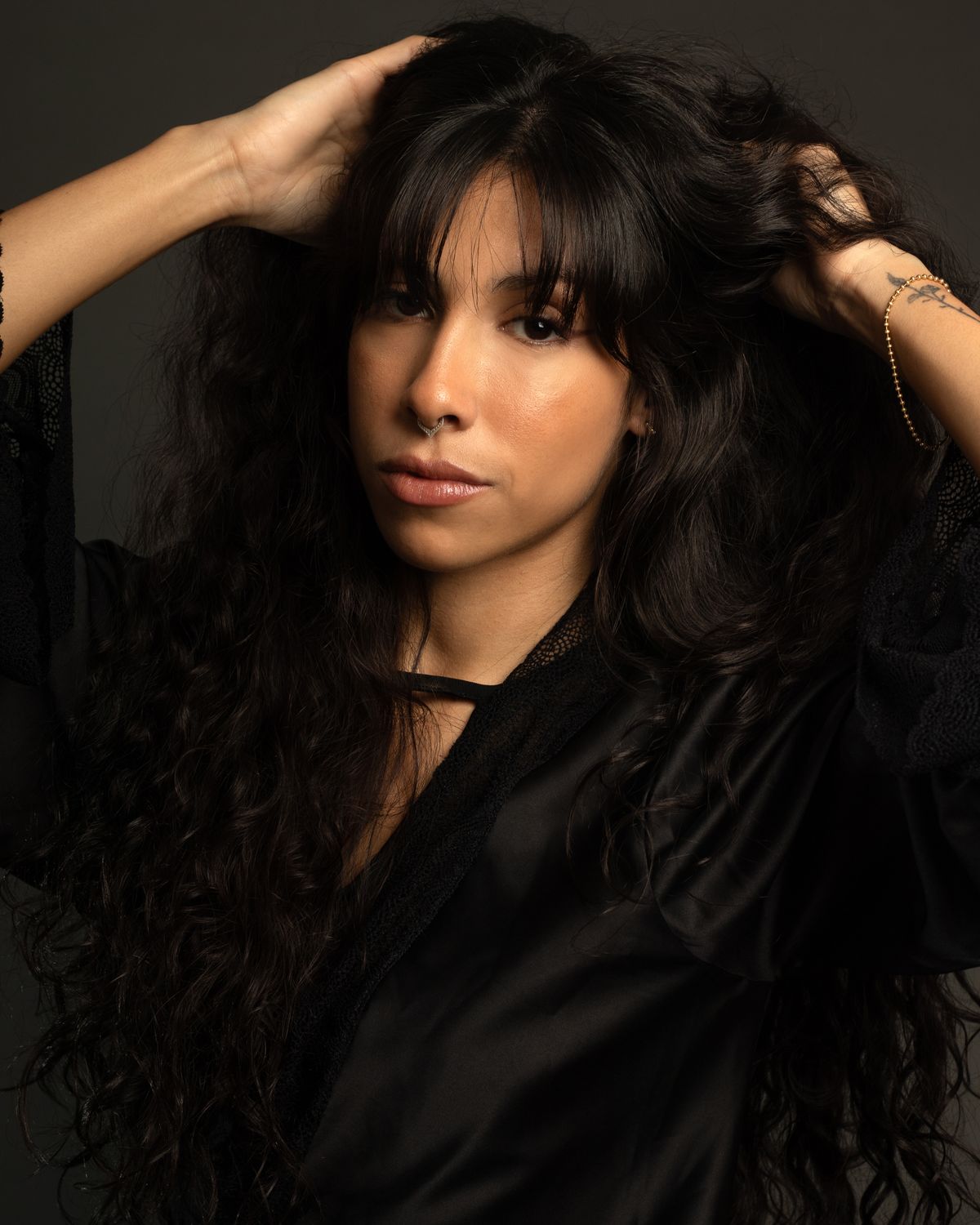 A dark lustrous blouse worn in soft light