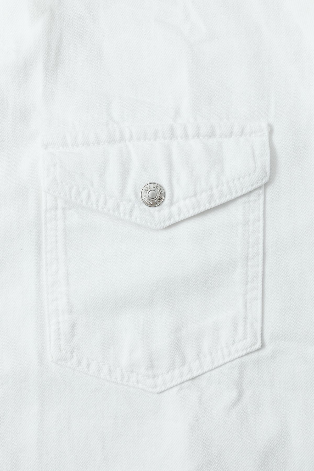 A close view of a white shirt pocket and button