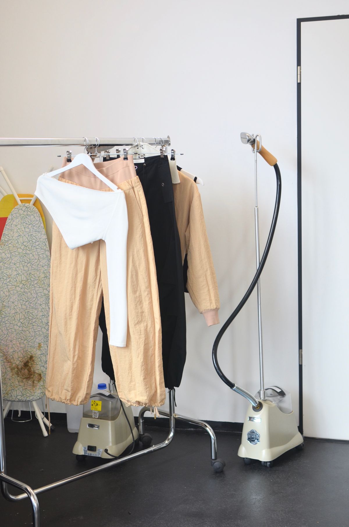 A garment steamer beside a rail of clothes