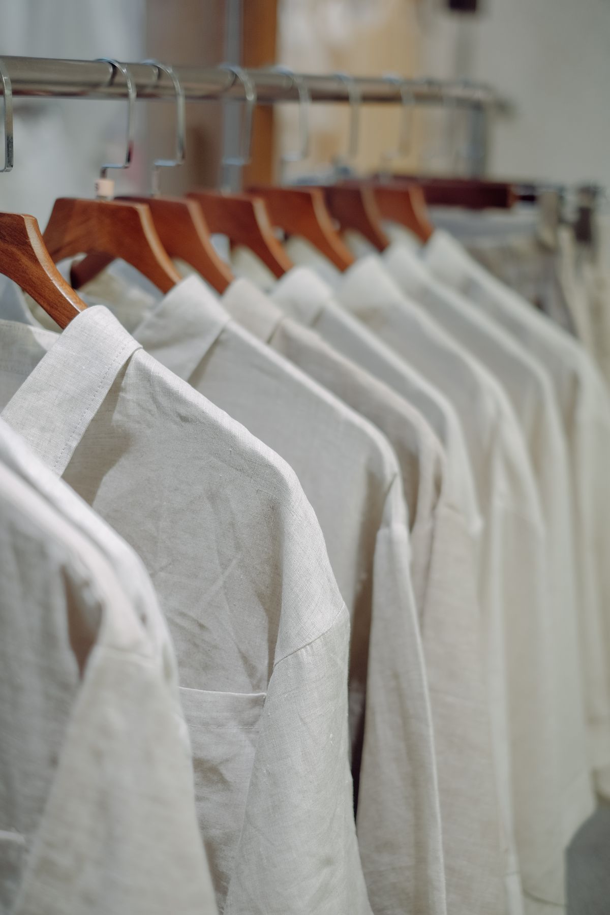 A row of white shirts on wooden hangers