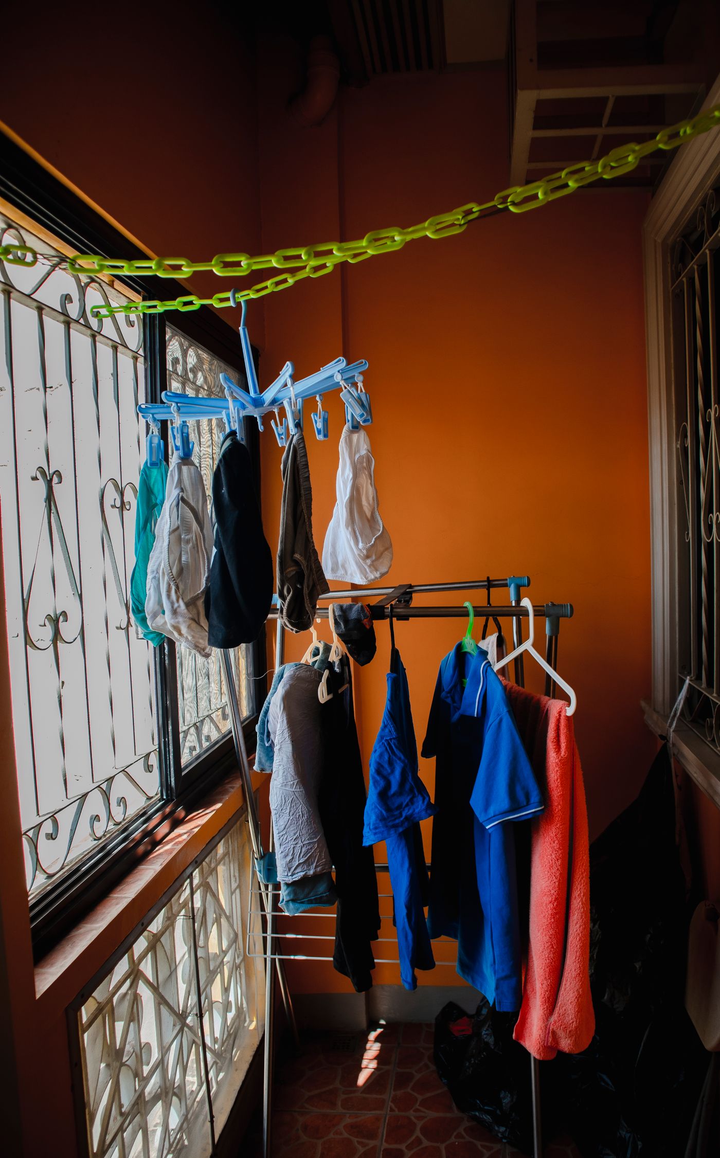 Clothes hanging with space between them beside open windows