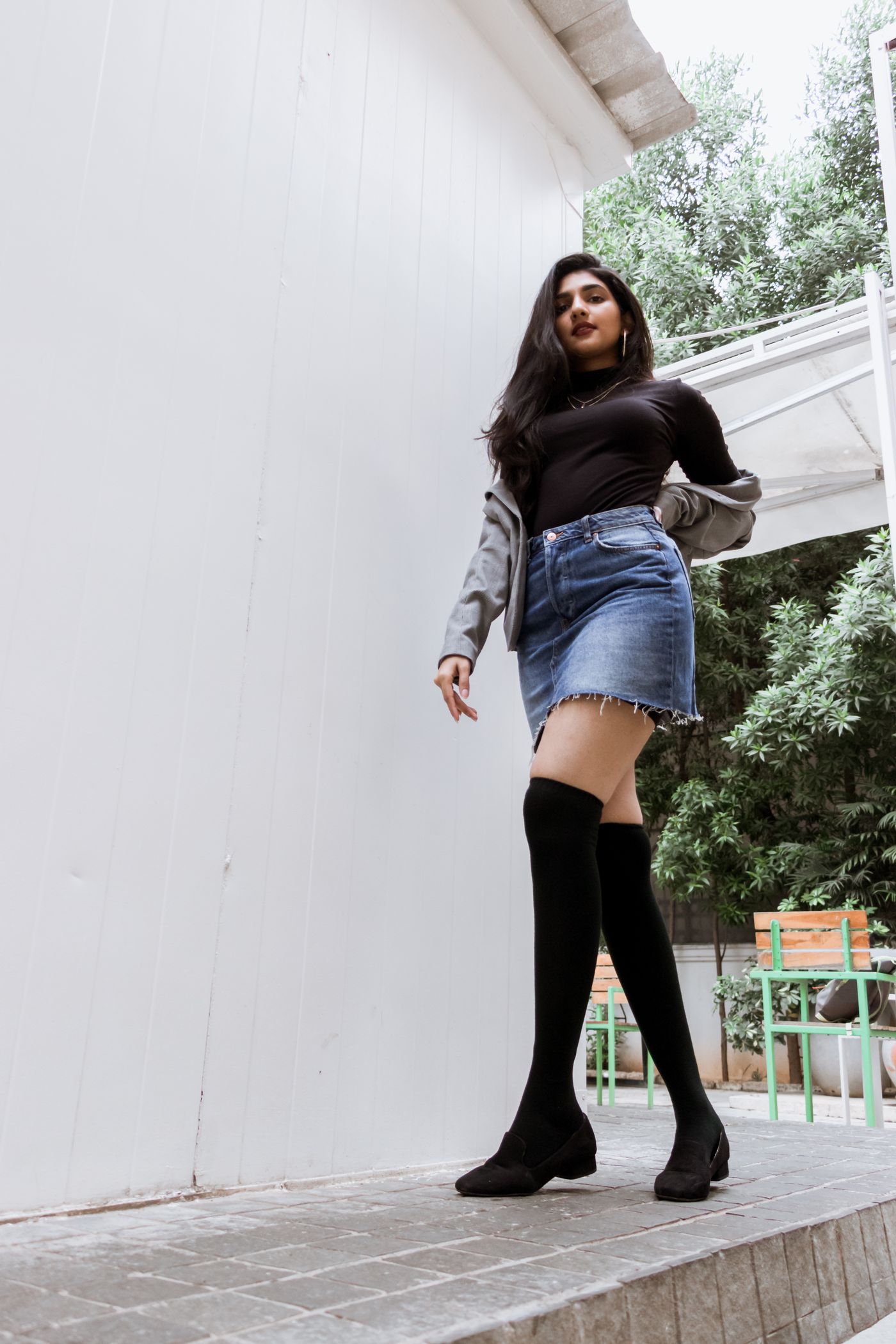 Tall black boots worn with a denim skirt