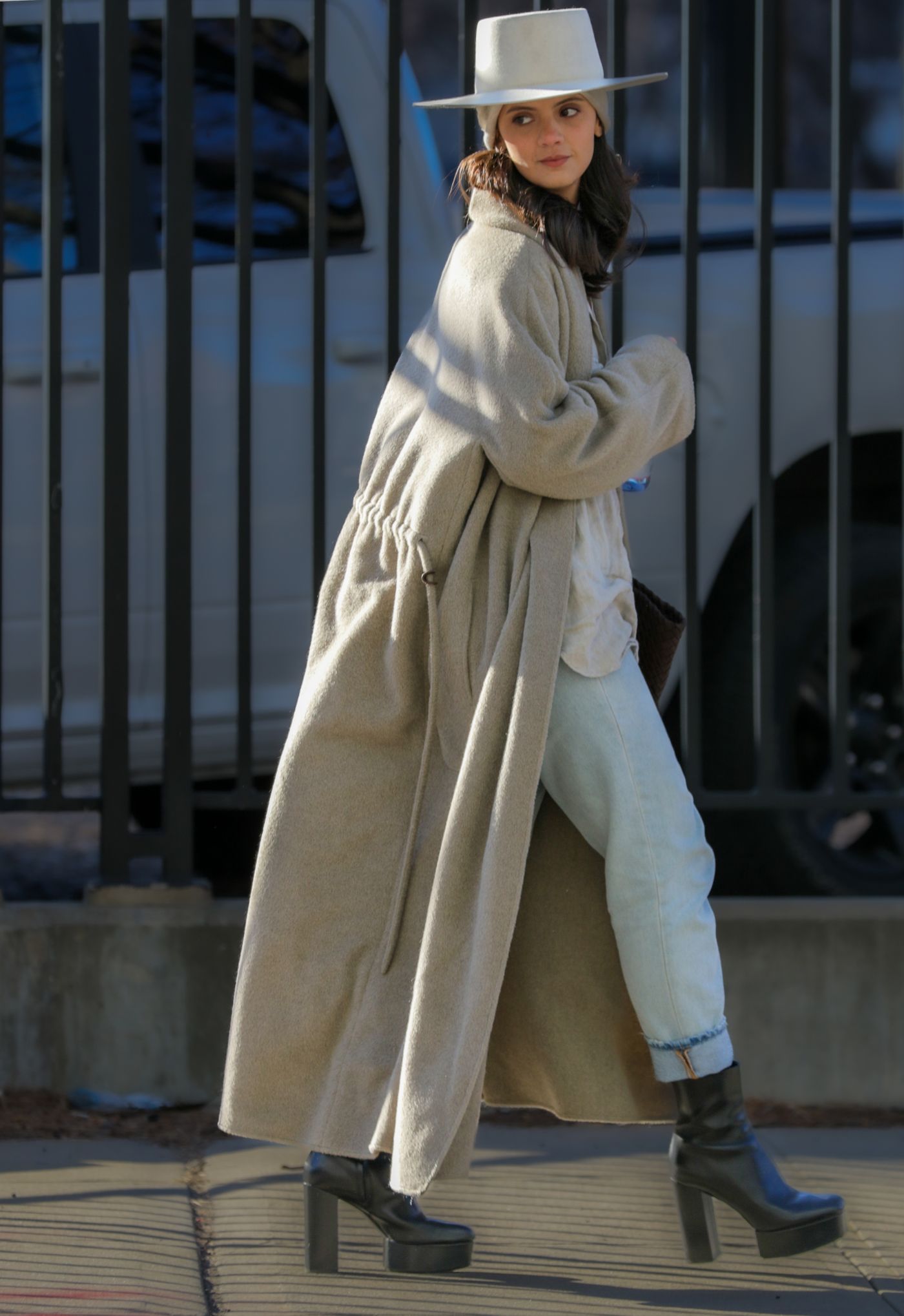 A hat worn with a long light-coloured coat