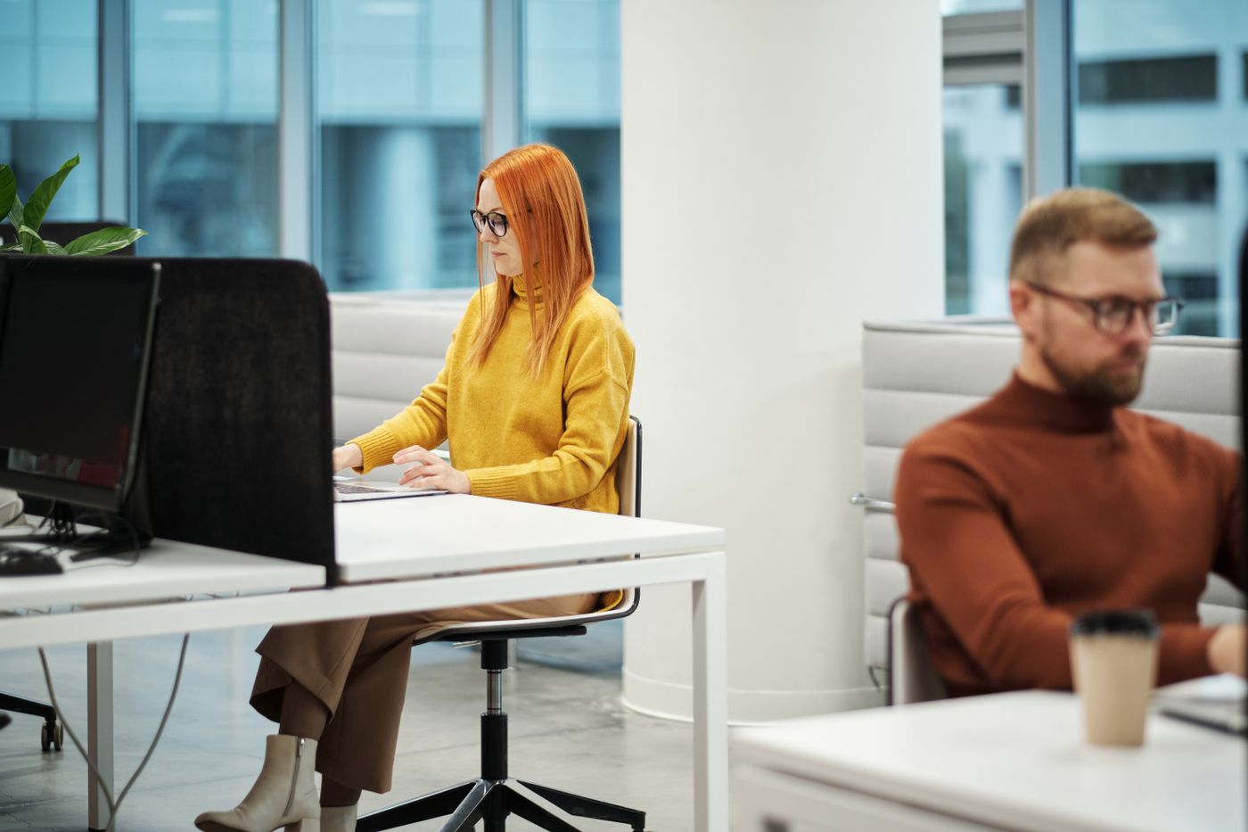 A woman in a yellow hooded top at an office desk