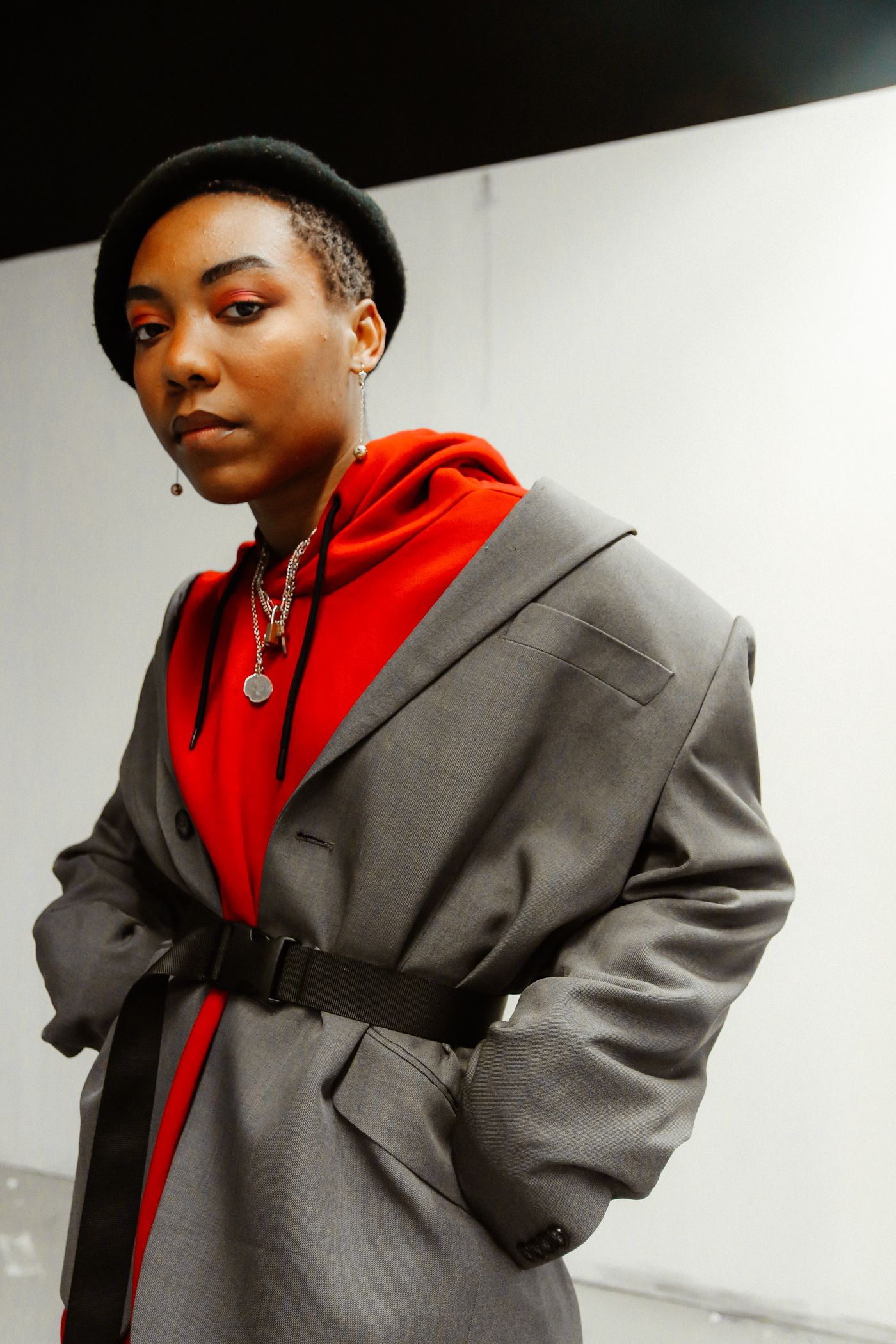 A grey coat layered over a red hooded top