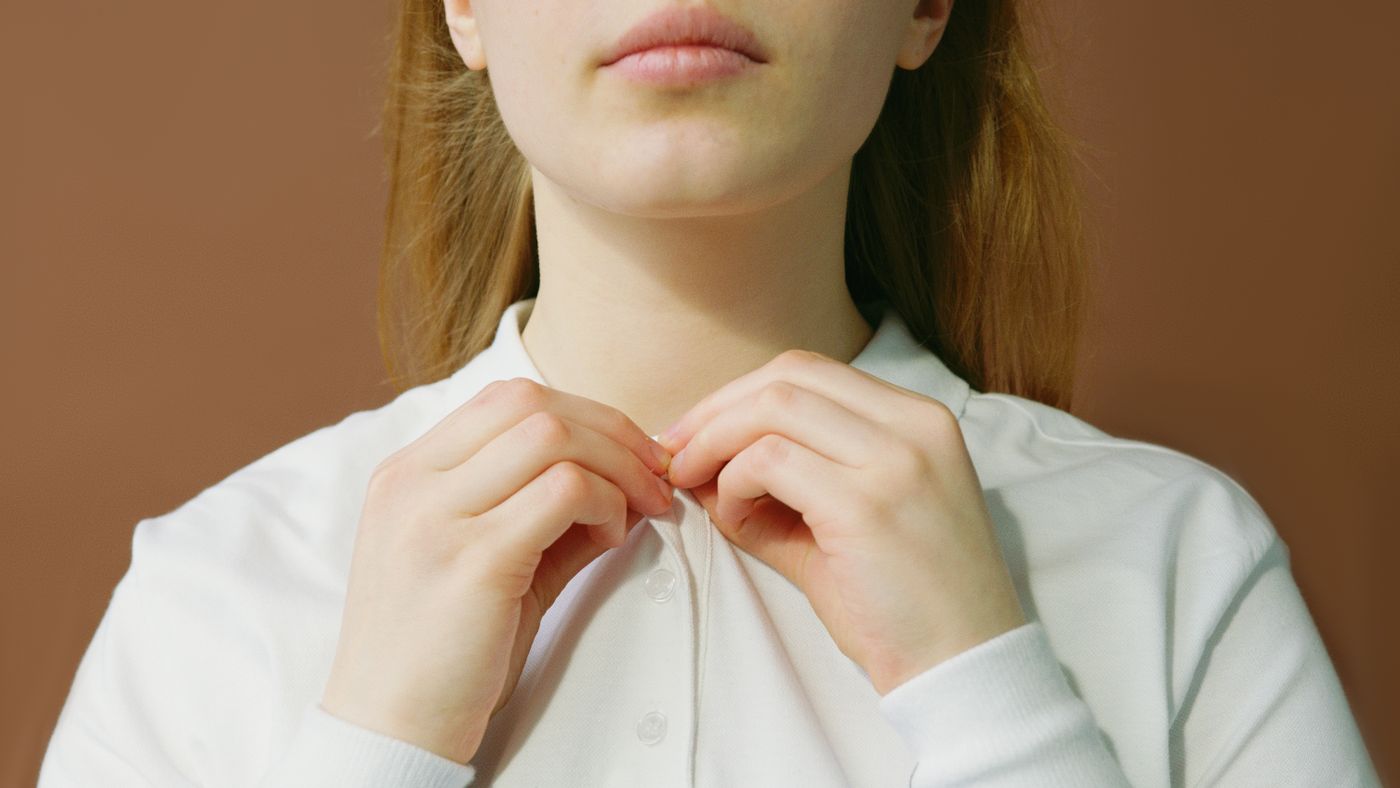Hands fastening the buttons of a white shirt